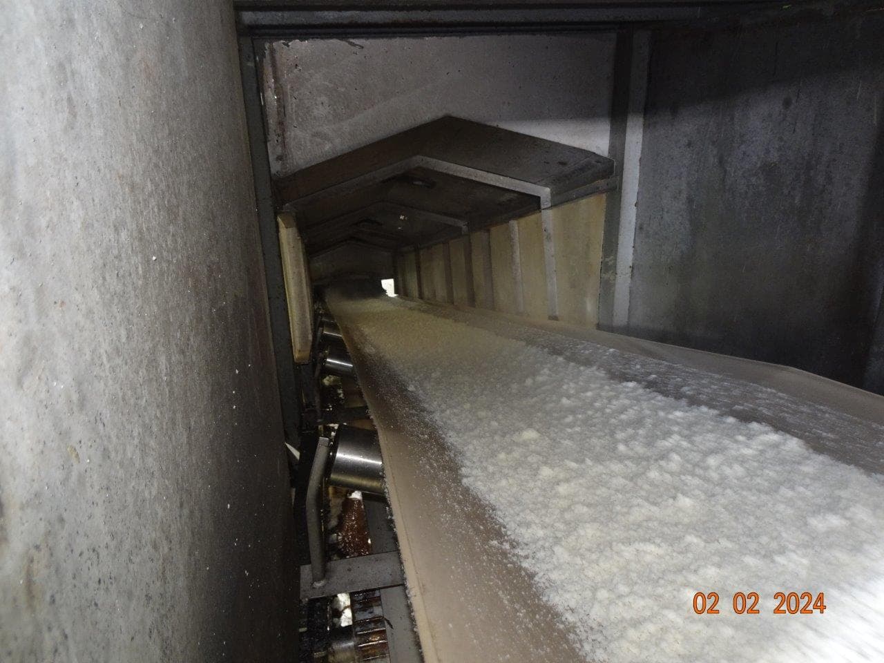 White pellets moving along an enclosed conveyor